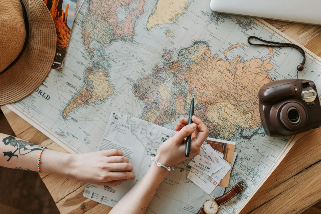 A woman with a hat on, looking at a world map. 
